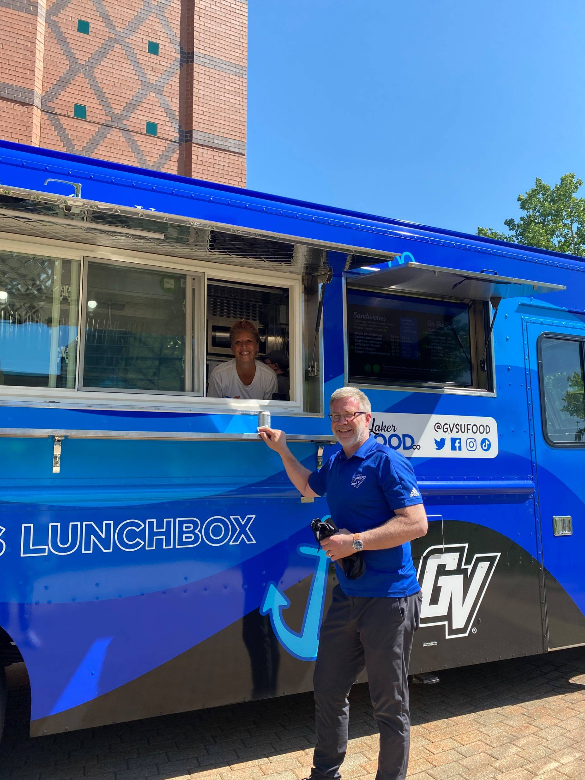 Mark Schaub posing with Louie's Food Truck, parked near the Cook Carillon Clocktower